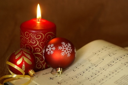 sheet music for classic Christmas song Adeste Fidelis with a red candle and red ornaments (Credit: Magdalena Kucova via iStockphoto)