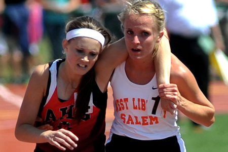 Meghan Vogel of West Liberty-Salem, right, helps Arden McMath of Arlington to the finish line after McMath collapsed yards short in the DIII 3200 meter finals of the Ohio High School Athletic Association state track meet at Jesse Owens Stadium in Columbus, June 2, 2012 (Credit: Piqua Daily Call/Mike Ullery)