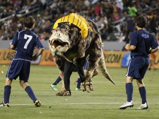 A Tyrannosaurus Rex dinosaur costume runs on the field as young boys play an exhibition soccer match during halftime of the MLS soccer game between the Los Angeles Galaxy and Seattle Sounders FC in Carson, California to promote the Natural History Museum of Los Angeles County, May 26, 2013 (Credit: Reuters/Danny Moloshok)