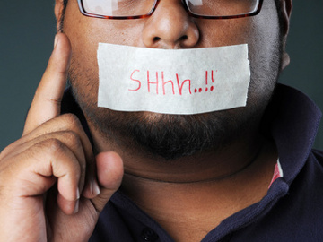 man with a silent message sticker on his mouth and hand shows warning (Credit: gezzeg via Fotolai)