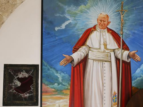 A broken glass of a niche where the reliquary with the blood of the late Pope John Paul II was located is seen next to a painting of the late Pope in the small mountain church of San Pietro della Ienca, near the city of L'Aquila January 28, 2014 (Credit: Reuters/Max Rossi)