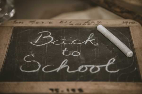 Hand-held chalkboard framed in wood that says Back to School