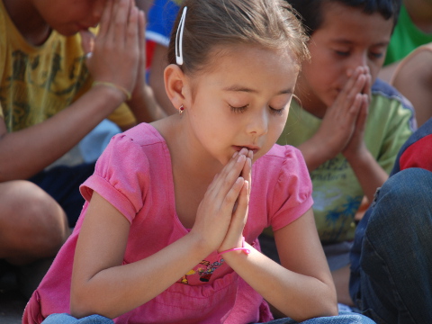 A young Honduran girl prays with a group of children from her village during a visit from Olivet Nazarene University students on Mission In Action mission trip, March 9, 2011 (Credit: Cassidy Lancaster via Flickr)