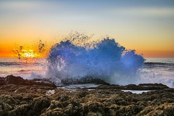 https://unsplash.com/photos/a-wave-crashing-on-a-rocky-shore-at-sunset