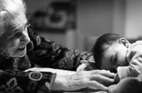Senior Citizen female lovingly touching her sleeping grandbaby