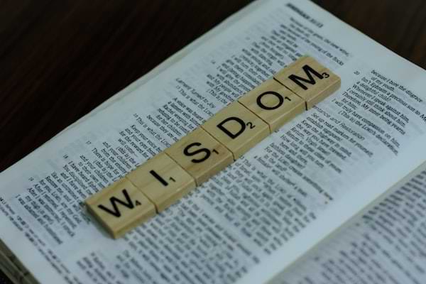 scrabble blocks on a page in the Bible that spell 'wisdom'