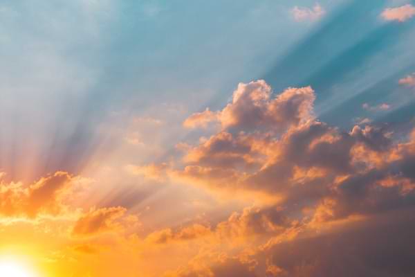 Sun filtering through the clouds with a blue sky backdrop