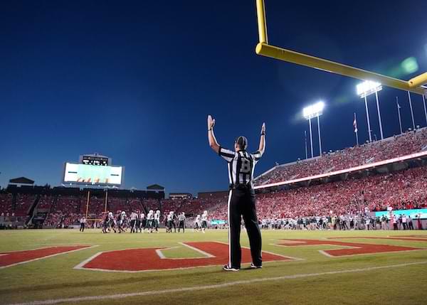 Referee under a football goal post with hands in goal post position indicating a touchdown
