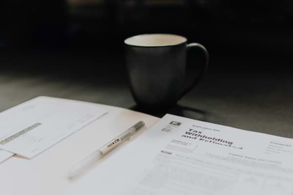 Tax forms laying on a table next to a cup of coffee