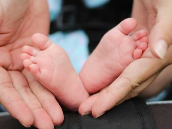 A mother's hands cradling her baby's feet