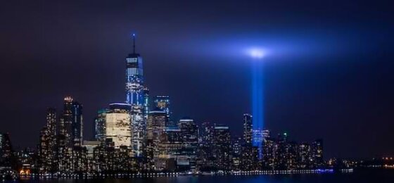 Skyline of Manhattan with two blue lights shining upward where the twin towers once were
