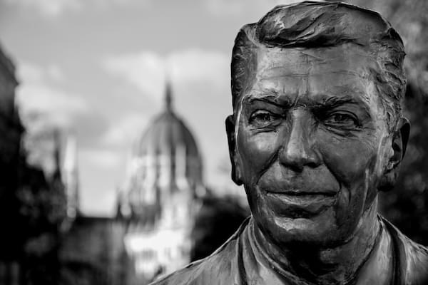 A close up of Ronald Reagan's face on a bronze statue in Washington D.C., with the Capital in the background.