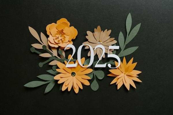 Paper orange flowers on a black drop with white numbers, 2025, imprinted on them