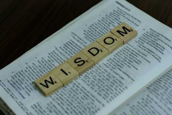 Scrabble letters spelling out wisdom on top of a Bible open to Proverbs