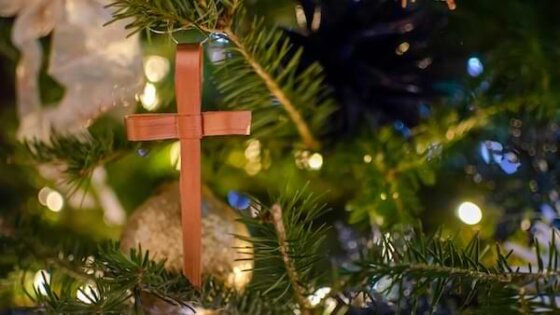 A closeup shot of a christmas tree branch with a brown leather cross