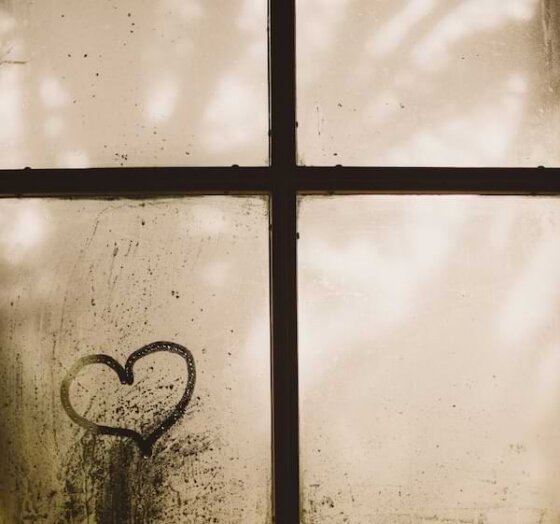A black and white image of a window pane that resembles a cross, and a small heart drawn in the bottom right pane.