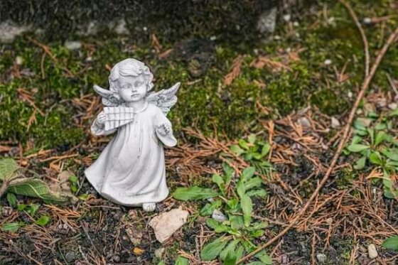ceramic-angel figurine playing a harp on brown dried leaves.